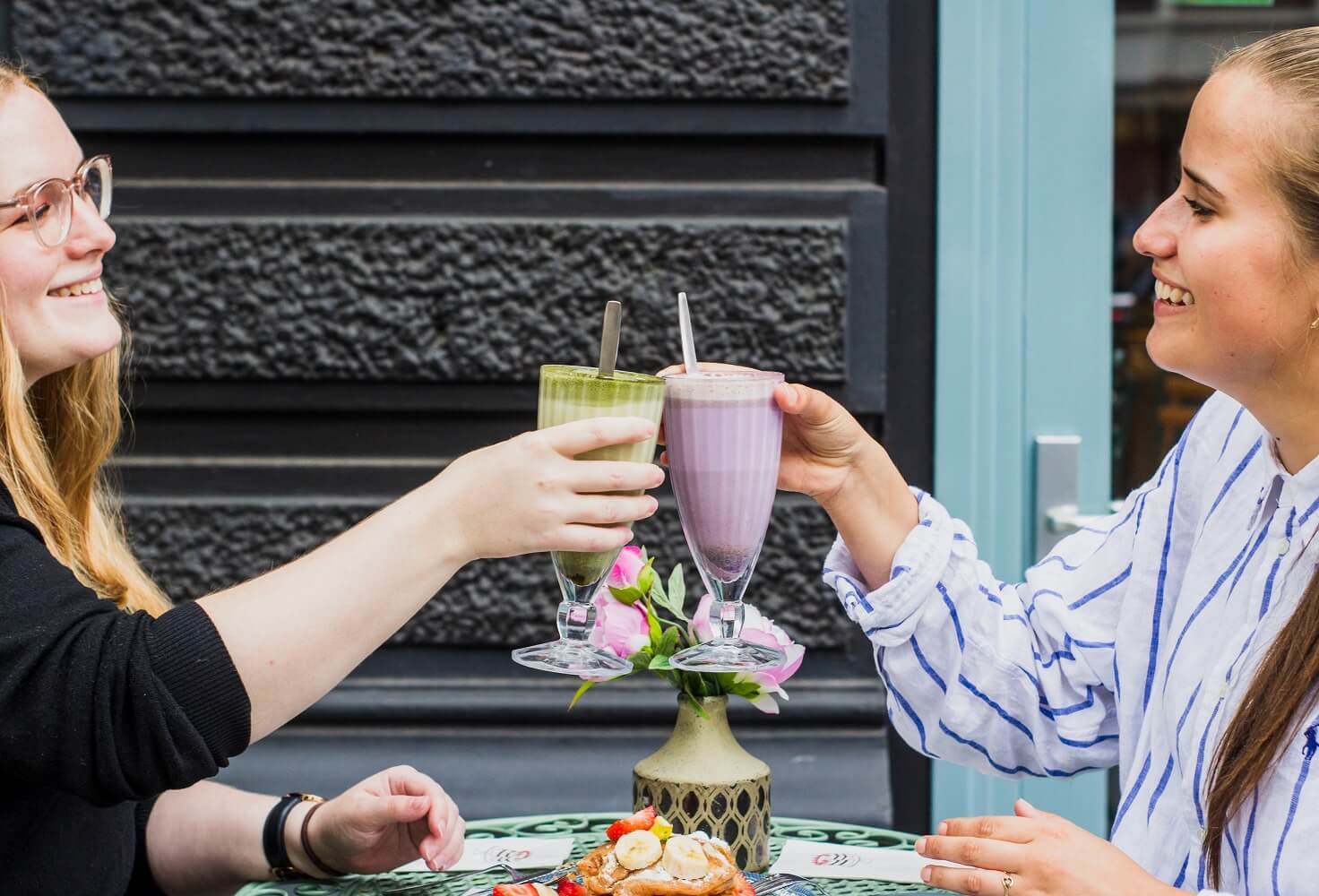 Two women on an outdoor table with green and purple smoothies that keep you full 