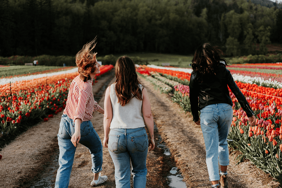 Three joyful women strolling through a field of blooming tulips